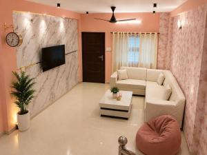 a living room with a white couch and a tv at Villa by Stay Junction in Indore