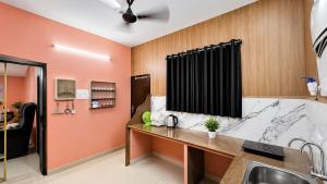 a kitchen with orange walls and a counter with a sink at Villa by Stay Junction in Indore