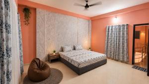 a bedroom with orange walls and a bed and a chair at Villa by Stay Junction in Indore +7 photos