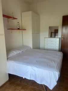 a bedroom with a white bed and a dresser at Casa COMER GRISOLIA in Cirella