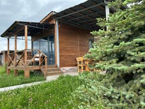 a wooden cabin with a porch and a tree at V&V Hotel in Gyulagarak