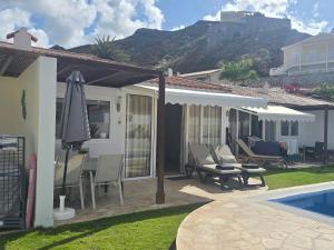 a house with a pool and a patio with an umbrella at Apartamento relax Tauro in Mogán