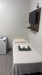 a bedroom with a bed with a tv on the wall at Hotel Tropical in Aquidauana