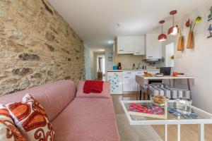 a living room with a pink couch and a kitchen at roomPEDRA apartamentos turísticos in Santiago de Compostela