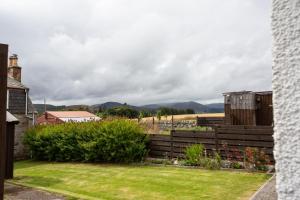 a garden with a fence and mountains in the background at 3BR Cottage with Garden, Free Parking for 6 Guests in Alness