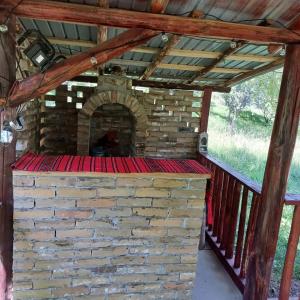 an outdoor fireplace in a house with a brick wall at La tataie Nucșoara in Nucşoara