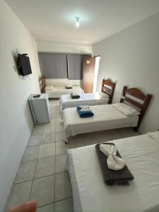 a hotel room with three beds and a tv at Hotel Tropical in Aquidauana +51 photos