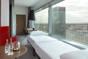 a hotel room with two beds and a large window at Meliá Paris La Défense in Courbevoie