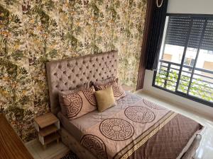a bed with pillows in a room with a wall at Studio Luxe Bouznika Beach Piscine, Clim, Wi-Fi ,Check in 24h Plage 5 min in Bouznika +28 photos