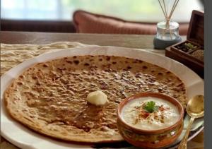 a pizza sitting on a table with a bowl of dip at Giovanni Suites in Bhopal +33 photos
