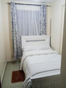 a bedroom with a white bed and a window at Halcon Homes Machakos Boma Yangu in Machakos