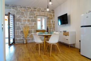 a dining room with a table and chairs and a stone wall at Nada Apartment near Krka National Park in Skradin