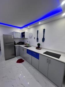 a kitchen with white cabinets and blue lights on the wall at Private Oasis with Jacuzzi & Pool for Two in Ciales