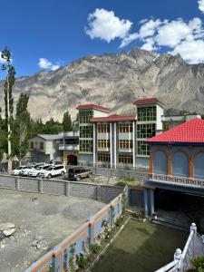 a hotel with cars parked in front of a mountain at cloudrestskardu in Skardu