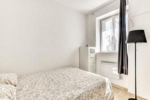 a white bedroom with a bed and a window at La Petite Maison - T1 Bis in Peyriac-de-Mer