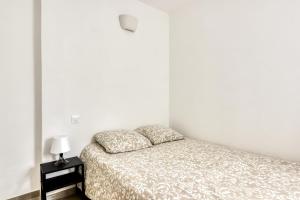 a bedroom with a bed and a lamp on a night stand at La Petite Maison - T1 Bis in Peyriac-de-Mer