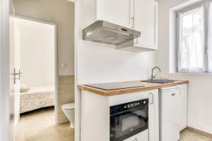 a white kitchen with a sink and a stove at La Petite Maison - T1 Bis in Peyriac-de-Mer