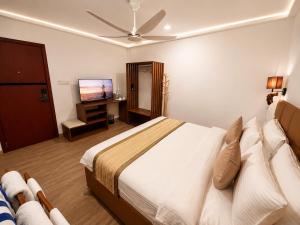 a bedroom with a bed and a flat screen tv at Cocomo Maldives in Himmafushi