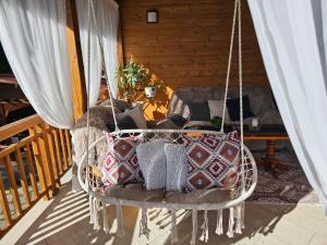 a hanging chair with pillows on a porch at Villa Hills - къща за гости с храна in Orlino