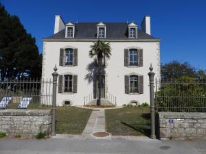 a white house with a palm tree in front of it at Ty Kabiten appartement VUE MER in Locmariaquer