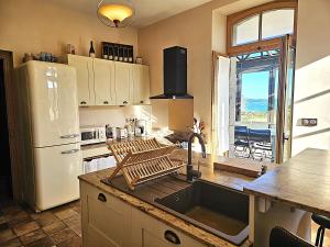 a kitchen with a sink and a white refrigerator at Ty Kabiten appartement VUE MER in Locmariaquer