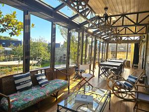 a conservatory with a couch and tables and windows at Ty Kabiten appartement VUE MER in Locmariaquer +3 photos