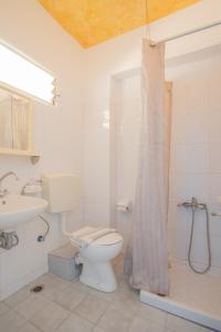 a white bathroom with a toilet and a shower at Blue White House in Kalamitsi +27 photos
