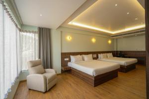a hotel room with two beds and a chair at Tiger Hill Hotel & Suites in Kalpetta +18 photos