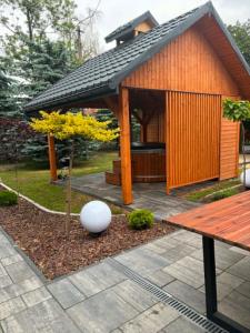 a small wooden pavilion with a bench and a tree at LUX HOUSE Roztocze 1 in Krasnobród