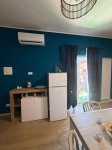 a kitchen with a blue wall with a refrigerator and a table at Sciuri House in CTA