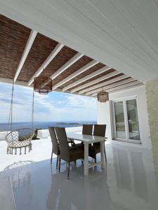 a table and chairs on a patio with a view of the ocean at Eolia luxury suites Andros in Batsi