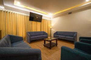 a waiting room with two couches and a tv at Tiger Hill Hotel & Suites in Kalpetta