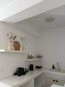 a white kitchen with a sink and a counter at Eolia luxury suites Andros in Batsi