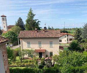 a large white house with a clock tower in the distance at La Canonica della Merella B&B in Novi Ligure