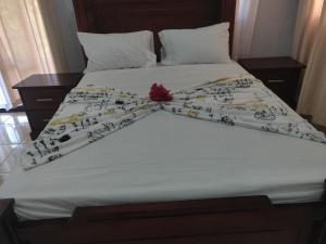 a bed with white sheets and a red flower on it at casa Verano in Cabarete