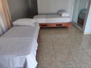 two beds in a room with a tiled floor at casa Verano in Cabarete +1 photo