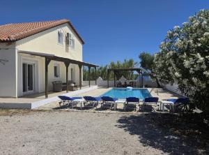 a swimming pool with chairs and a house at Villa Mari in Makris Gialos