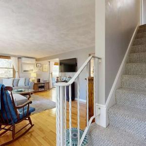 a living room with a staircase and a living room with a couch at Bay Pointe Bungalow in East Falmouth
