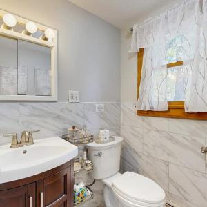 a white bathroom with a toilet and a sink at Bay Pointe Bungalow in East Falmouth +17 photos