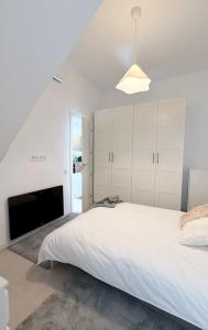 a white bedroom with a large bed and a tv at Posada de María Casa Cori 5 in Talavera de la Reina