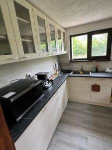 a kitchen with white cabinets and a black counter top at Къща за гости Зафирови in Ribarica