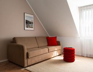 a living room with a couch and a red ottoman at Limehome Basel Town Hall in Basel +57 photos