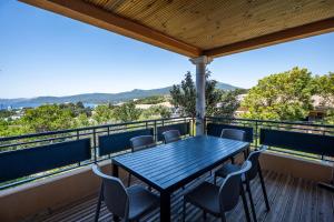 a deck with a table and chairs on a balcony at Résidence Guddelmoni, Piscines chauffées in Propriano