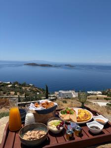 a table with food and a view of the ocean at Eolia luxury suites Andros in Batsi +27 photos