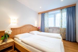 a bedroom with a white bed and a window at Residence Frea in Selva di Val Gardena