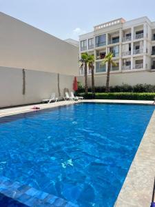 a large blue swimming pool in front of a building at Studio Luxe Bouznika Beach Piscine, Clim, Wi-Fi ,Check in 24h Plage 5 min in Bouznika