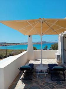 a patio with two chairs and an umbrella at Aktaea, Seaside Residence in Santa Maria