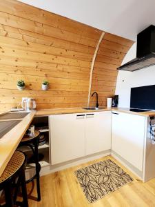 a kitchen with white cabinets and a wooden wall at L'éco-maison tout confort in Puisserguier