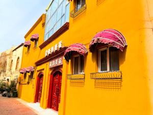 a yellow building with red doors and windows at Xinjiang Rhythm Hotel-疆韵民宿 in Kashgar