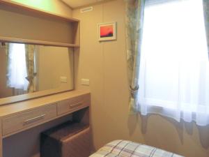 a bedroom with a dresser and a mirror at Windy Roost Lodge in Tydd Saint Giles